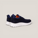 Rear heel view of a pair of navy suede laced design slip on sneakers with orange inner accents and a white sole